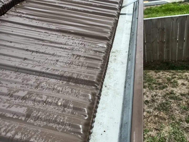 A cleared and washed gutter along a brown tile roof